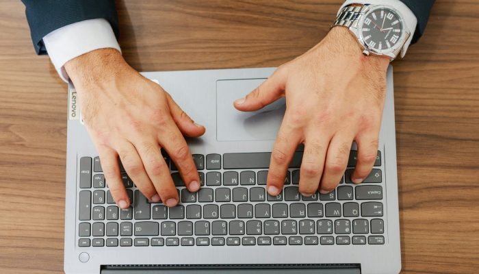 A person types on a laptop at a desk.