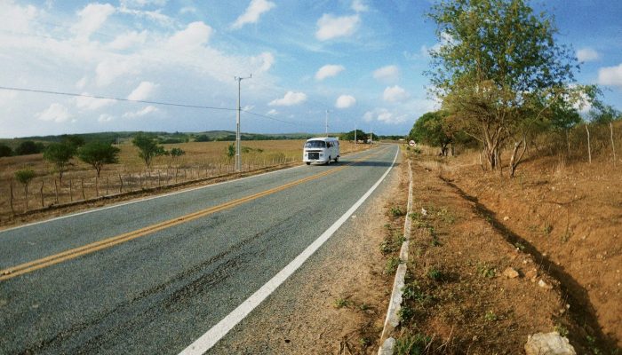 a white bus driving down a rural road
